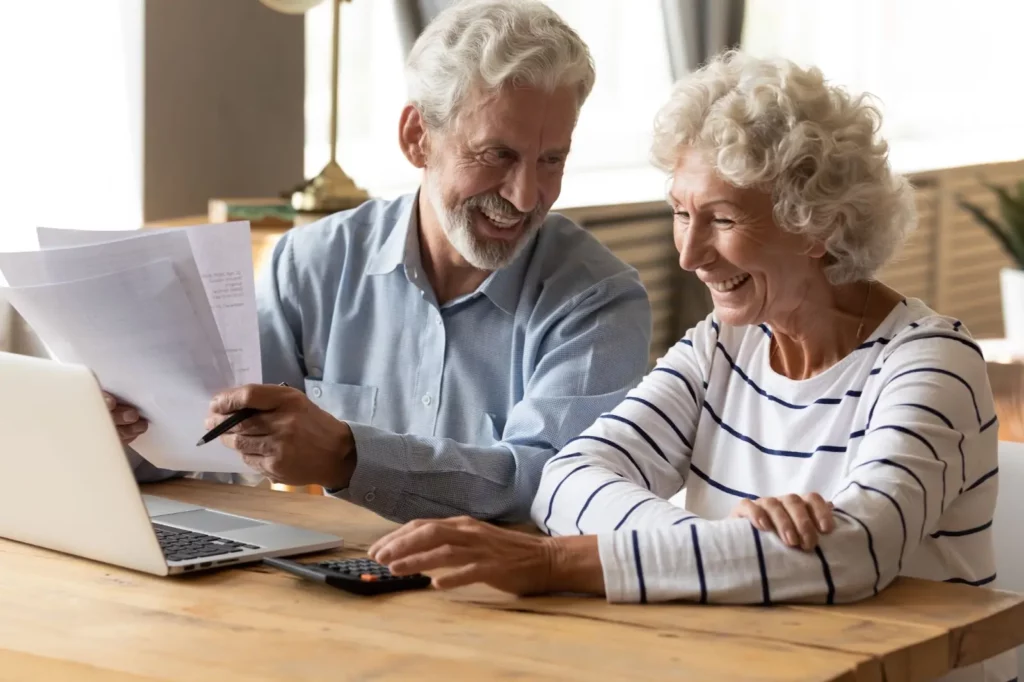 Elderly couple joyfully managing finances together at home.